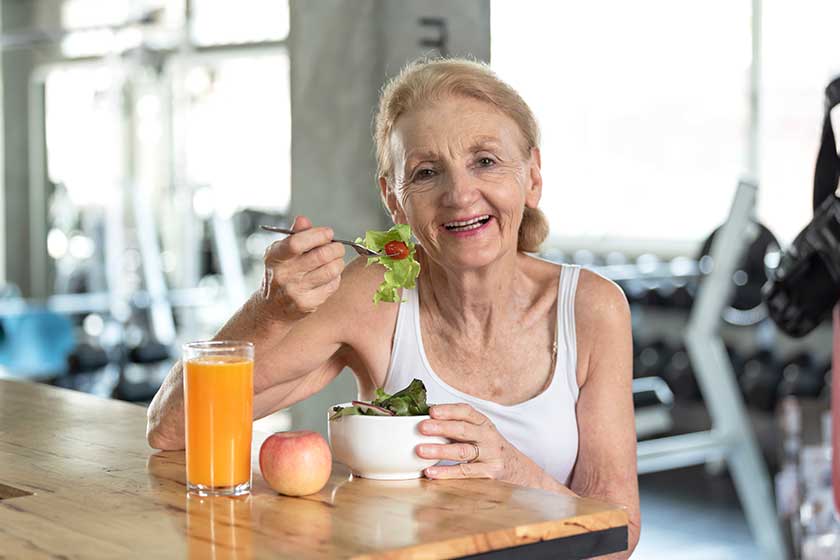 Senior woman eating healthy salad and orange juice. elderly health lifestyle concept