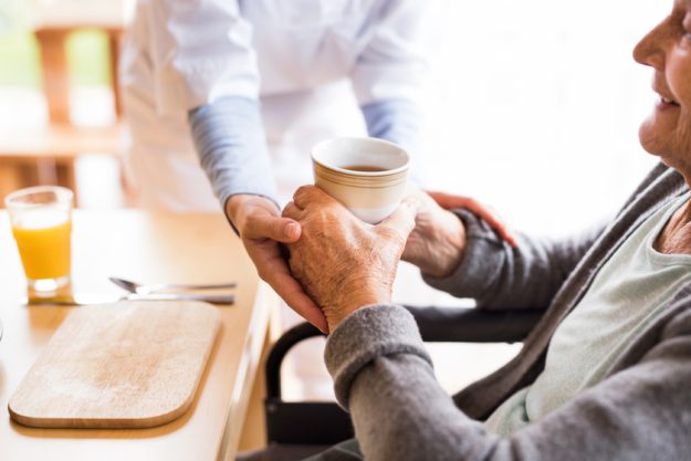 Unrecognizable health visitor and a senior woman during home visit.