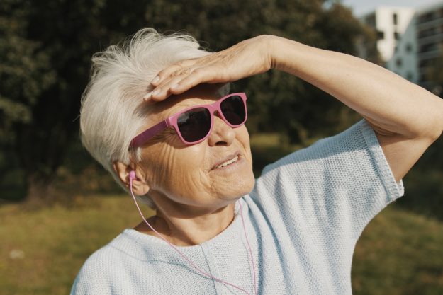 Senior woman with pink sunglasses in the park looking at the distance How Optimism In Seniors Leads To Better Health
