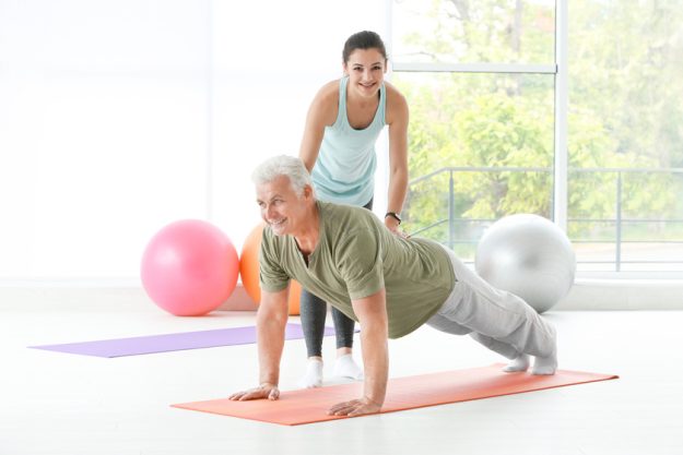 Instructor helping senior man to practice yoga in gym Seniors Balance Tips: How To Stay On Your Feet