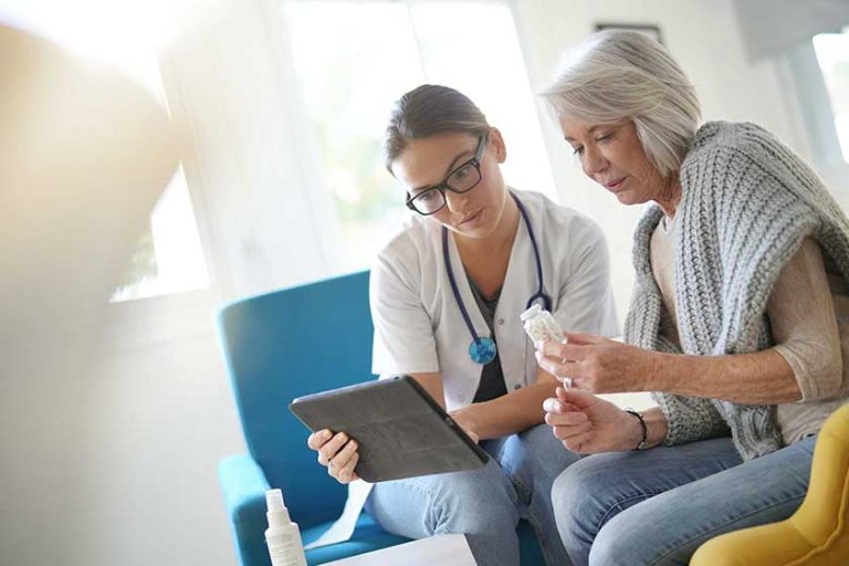Doctor going through results and medication on tablet with senior patient