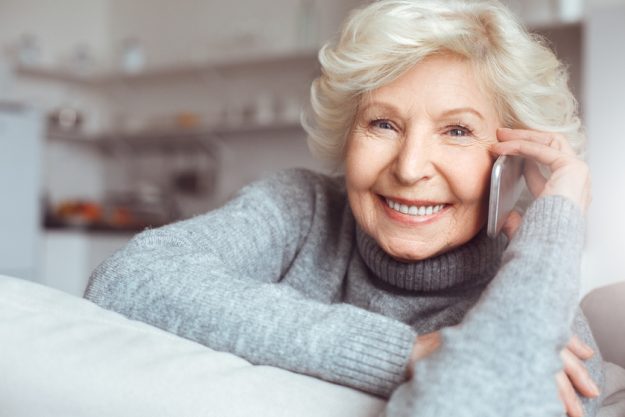 Portrait handsome grandmother in gray sweater talking on the phone How To Keep in Touch with Your Adult Children