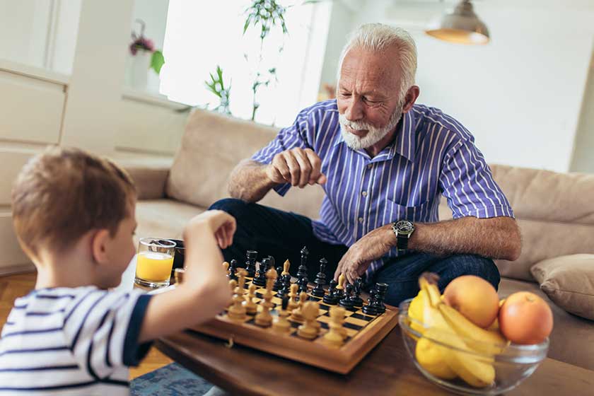 Young boy is playing chess with his grandfather at home
