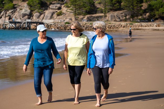 Group of three senior women walking having having fun on beach. Friendship and retirement lifestyle Traveling Tips In Your Golden Years