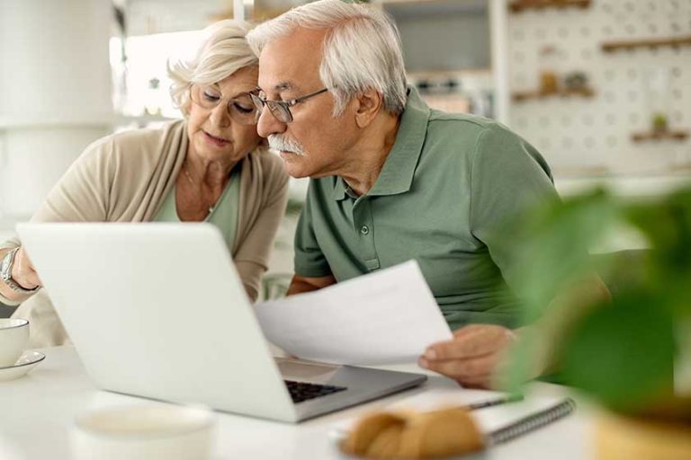 Mature couple using laptop while analyzing their bills