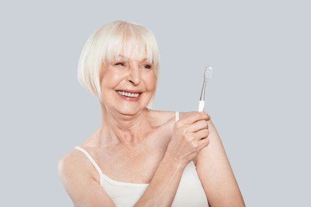Taking good care of teeth. Beautiful senior woman holding toothb Taking good care of teeth. Beautiful senior woman holding toothb