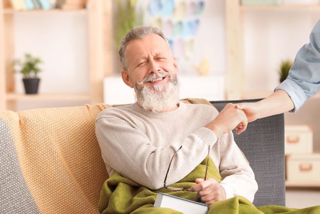 Senior man with young caregiver at home