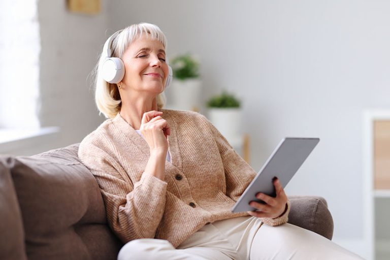 Elderly woman in headphones with tablet
