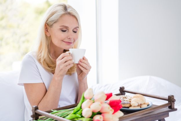 Photo of charming aged lady sit bed white linen drink smell fresh coffee beverage dreamer bedroom indoors Photo of charming aged lady sit bed white linen drink smell fresh coffee beverage dreamer bedroom indoors
