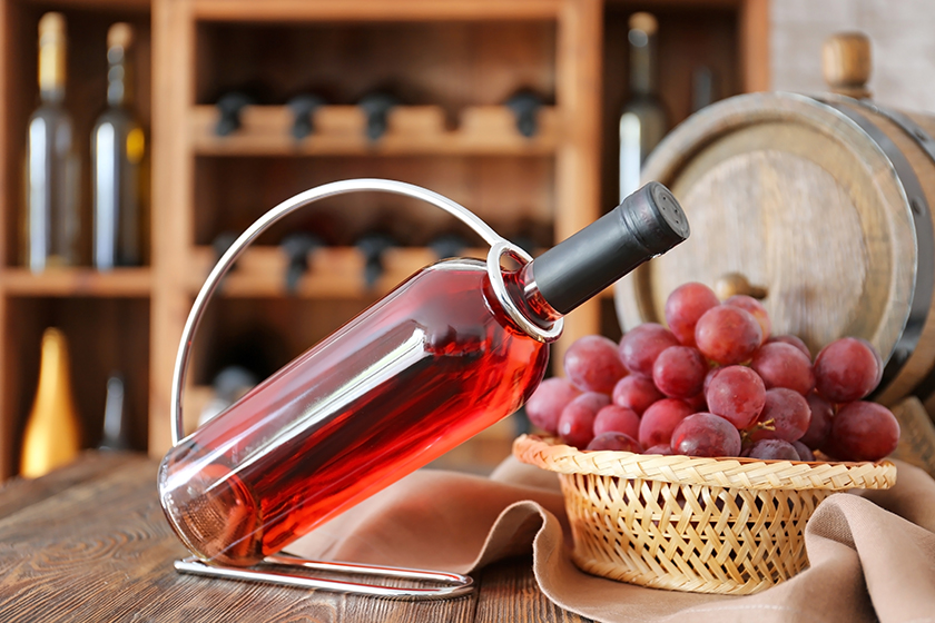 Holder with bottle of wine on table in cellar