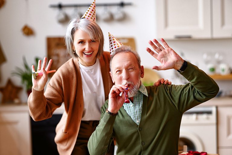 Positive elderly couple celebrating birthday at home