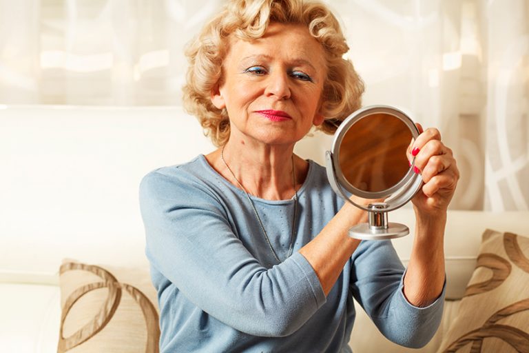 Smiling elderly woman comb and looked in the mirror