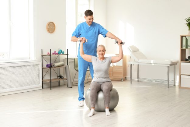 Physiotherapist working with patient in clinic. Rehabilitation t Physiotherapist working with patient in clinic. Rehabilitation t