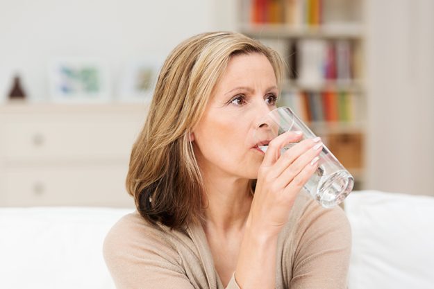 Thirsty woman drinking a glass of cold water