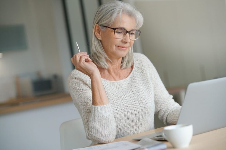 Senior woman at home websurfing on laptop computer