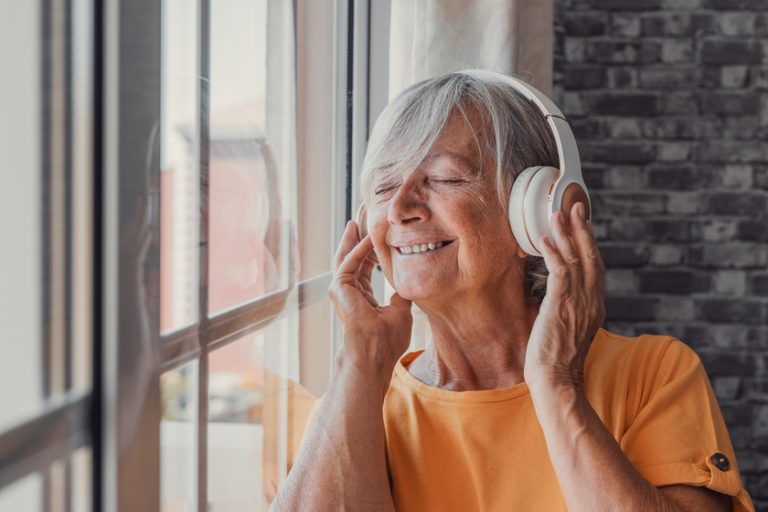 Side view happy old mature retired woman listening popular music