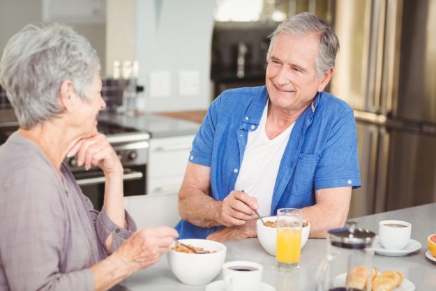 Happy senior couple talking while having breakfast at table