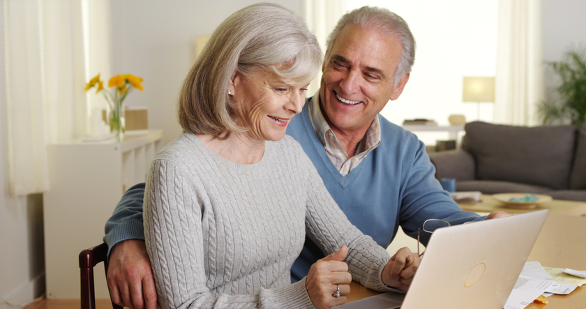 Happy mature couple using laptop computer to pay bills Happy mature couple using laptop computer to pay bills