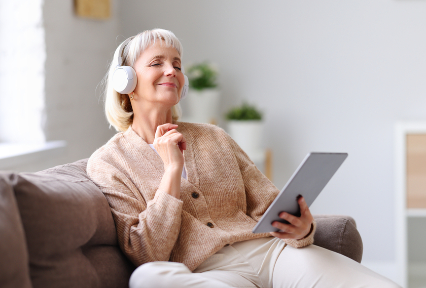 Senior woman listening to music sitting on sofa Senior woman listening to music sitting on sofa