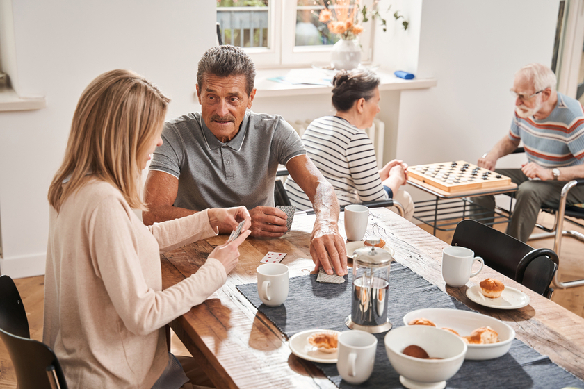Male pensioner sitting at the table with his caregiver and drinking tea Male pensioner sitting at the table with his caregiver and drinking tea