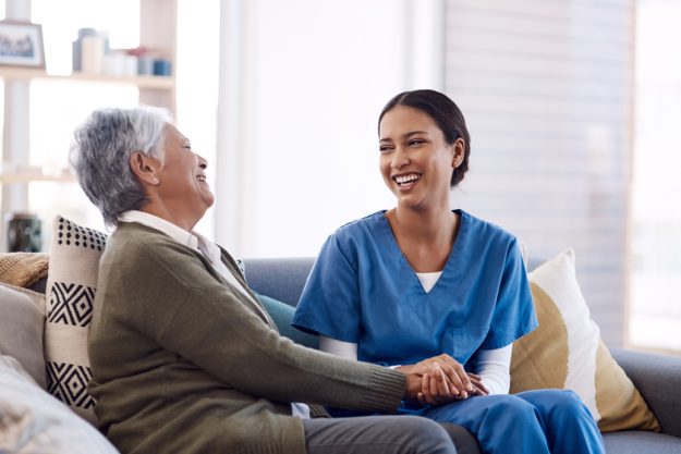 Consulting, caregiver and elderly woman laughing on sofa and holding hands in home living room. Support or healthcare, happy and female nurse talking or communication with senior citizen on a couch Consulting, caregiver and elderly woman laughing on sofa and holding hands in home living room. Support or healthcare, happy and female nurse talking or communication with senior citizen on a couch