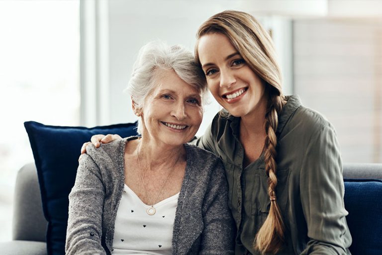 A senior woman and her adult daughter sitting together