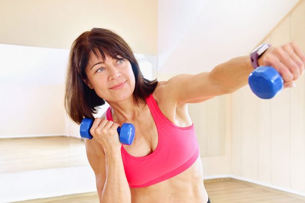 Fitness mature woman working out with dumbbells