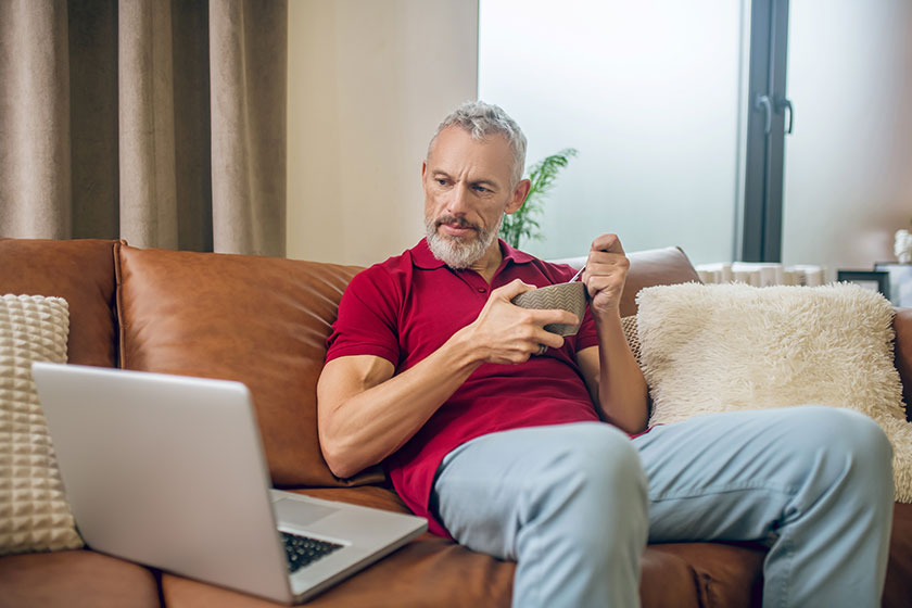 Grey haired man having lunch and watching a video