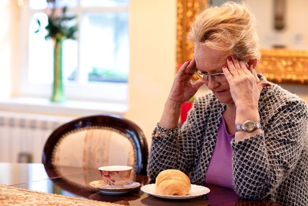 Older woman holding her head being depressed depression symptoms