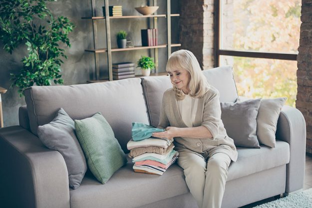 Portrait of her she nice attractive kind hardworking gray haired granny sitting on divan folding