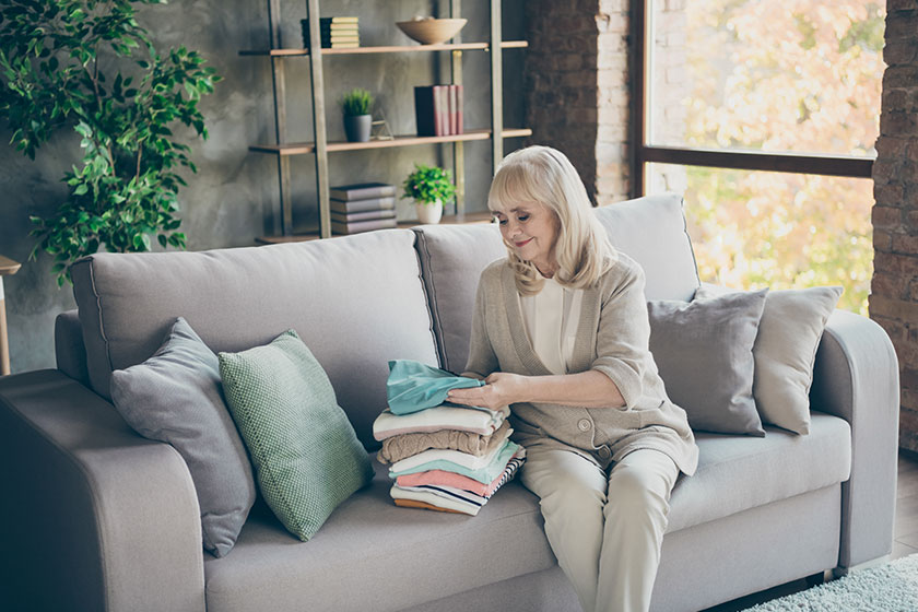 Portrait of her she nice attractive kind hardworking gray haired granny sitting on divan folding Portrait of her she nice attractive kind hardworking gray haired granny sitting on divan folding
