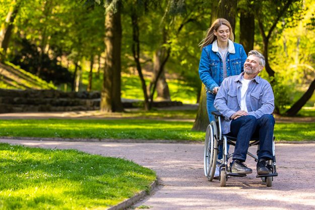 Good day woman rolling wheelchair her husband park both looking Good day woman rolling wheelchair her husband park both looking
