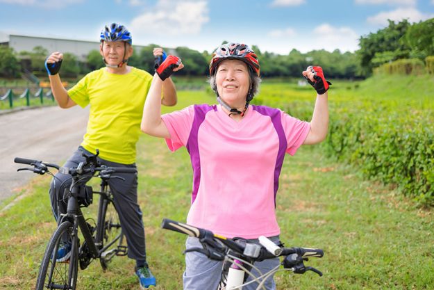 Happy healthy senior couple exercising with bicycles