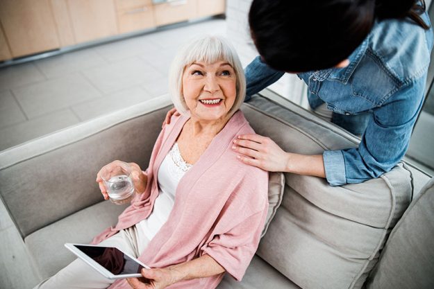 Old lady with gadget looking at granddaughter and smiling
