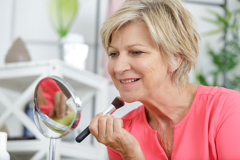 Senior woman in front of mirror putting makeup