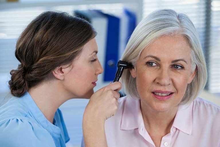 Doctor examining patients ear with otoscope