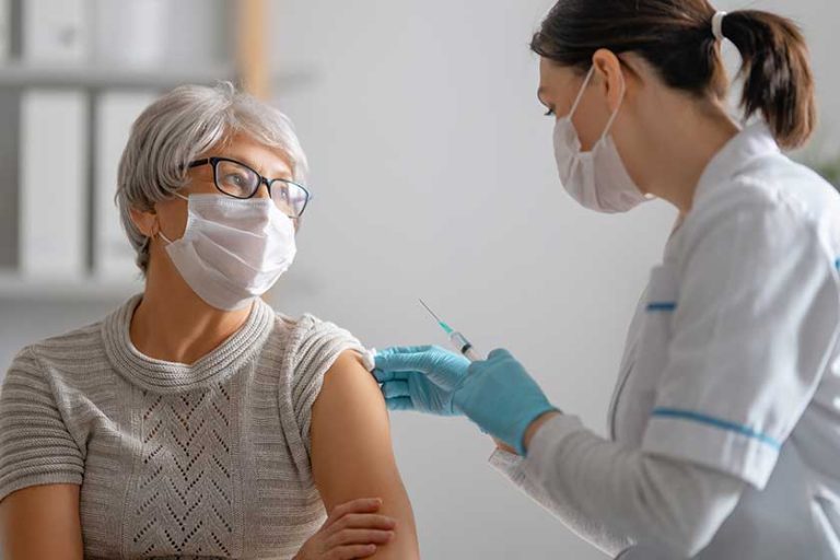 Doctor giving a senior woman a vaccination
