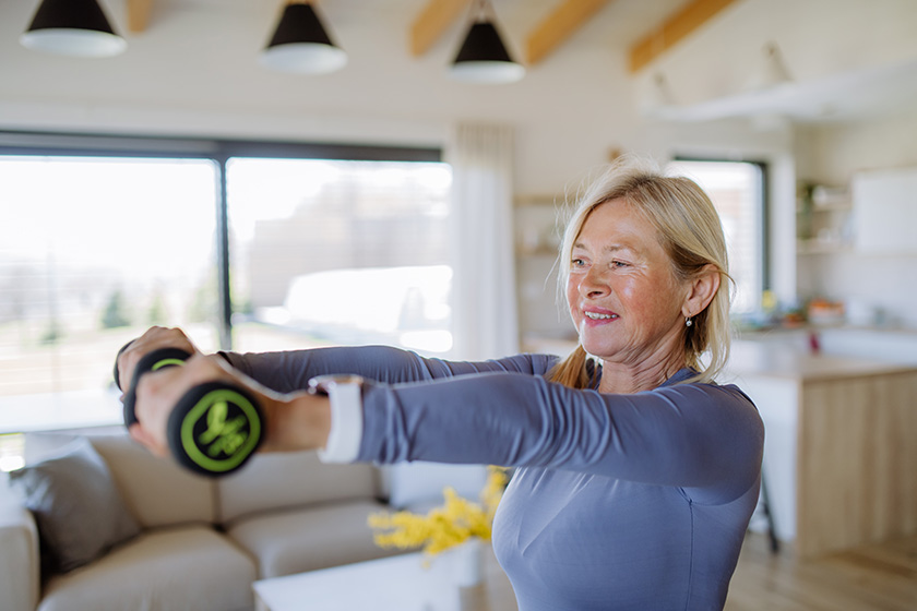 A fit senior woman exercising with dumbbells at home, active lifestyle concept. A fit senior woman exercising with dumbbells at home, active lifestyle concept.