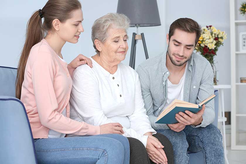 Grandmother with grandchildren reading book on sofa Grandmother with grandchildren reading book on sofa