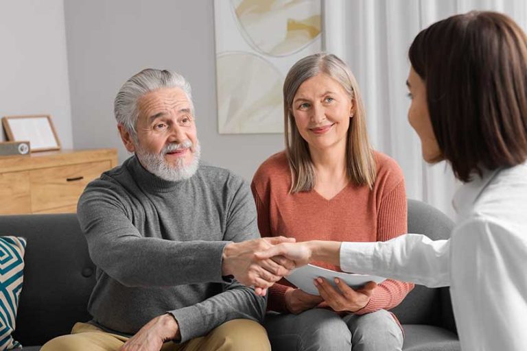 Insurance agent consulting elderly couple about pension plan in room
