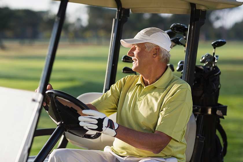 Mature man driving golf buggy