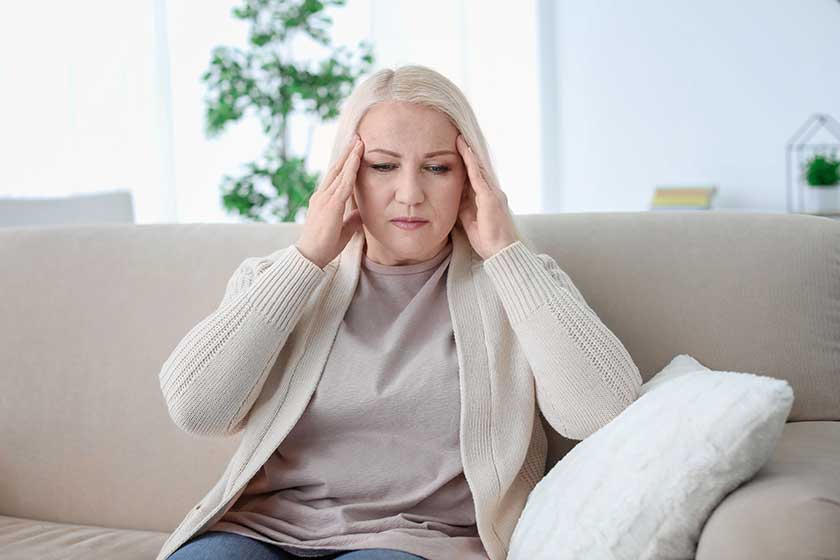 Mature woman suffering from headache while sitting on sofa at home Mature woman suffering from headache while sitting on sofa at home