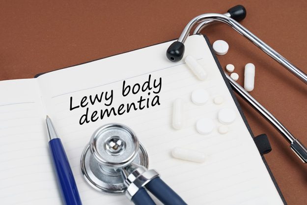 On a brown surface lie pills, a pen, a stethoscope and a notebook with the inscription - Lewy body dementia