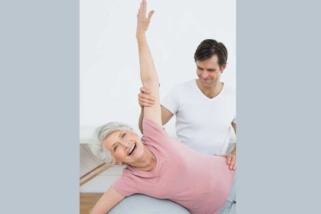 Physical therapist assisting senior woman with yoga ball Physical therapist assisting senior woman with yoga ball