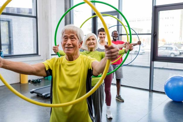 Positive interracial people holding hula hoops and looking at camera in gym Positive interracial people holding hula hoops and looking at camera in gym