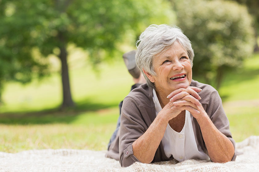 Smiling senior woman lying at park Smiling senior woman lying at park