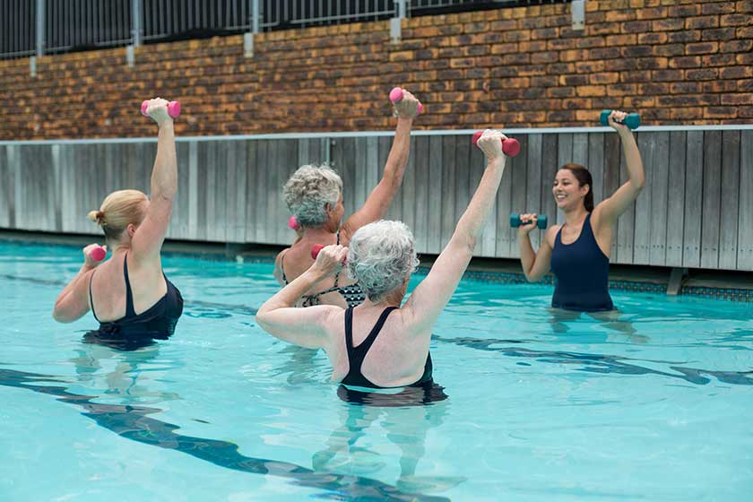 Trainer assisting senior women in weightlifting
