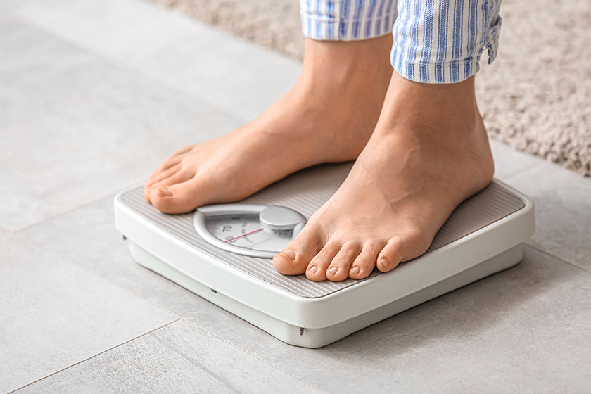 Young woman standing on scales at home