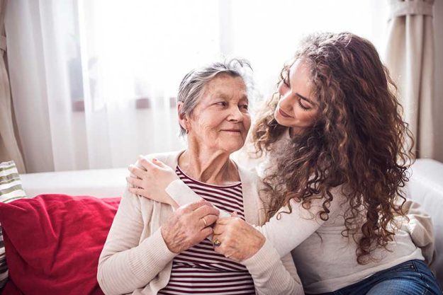 A teenage girl with grandmother at home, hugging.