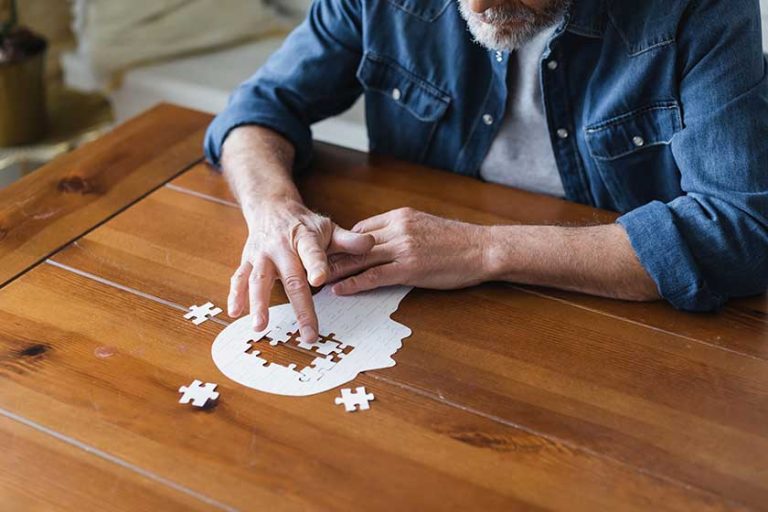 Elderly man with alzheimer folding puzzle